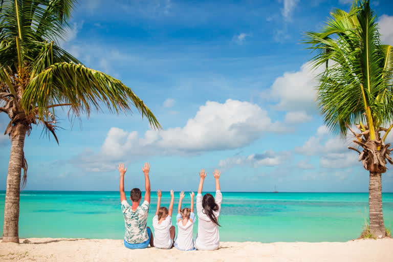 Father and daughters walking through a palm grove on a Florida beach